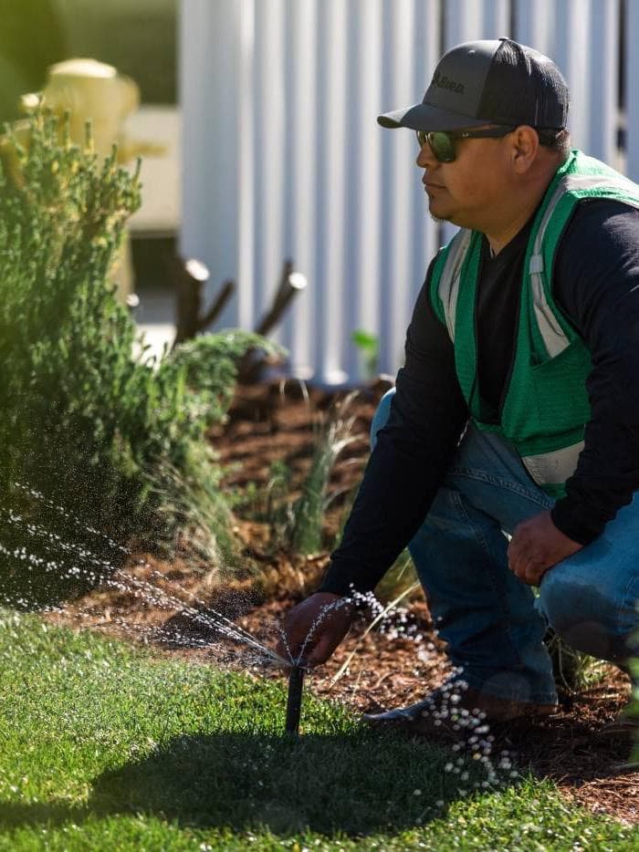 Irrigation technician adjusting a sprinkler on a commercial lawn